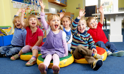 Group of children at childcare raising their hands