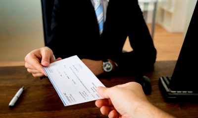 Man in a suit sat at a desk handing an employee an employment allowance slip