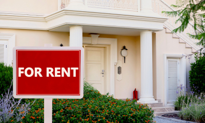 Beige property with a large red 'FOR RENT' sign by the door