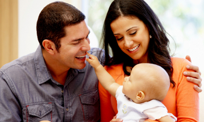 Young man and woman sitting smiling at their young baby