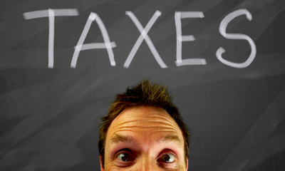 A man pops his head up below the work taxes on a blackboard