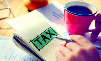 Tax written on notepad next to cup of coffee Tax written on notepad next to cup of coffee