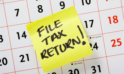 A yellow sticky note on a calendar marked ‘File Tax Return!’